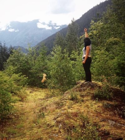 Kayla standing on a hillside among the trees and mountains